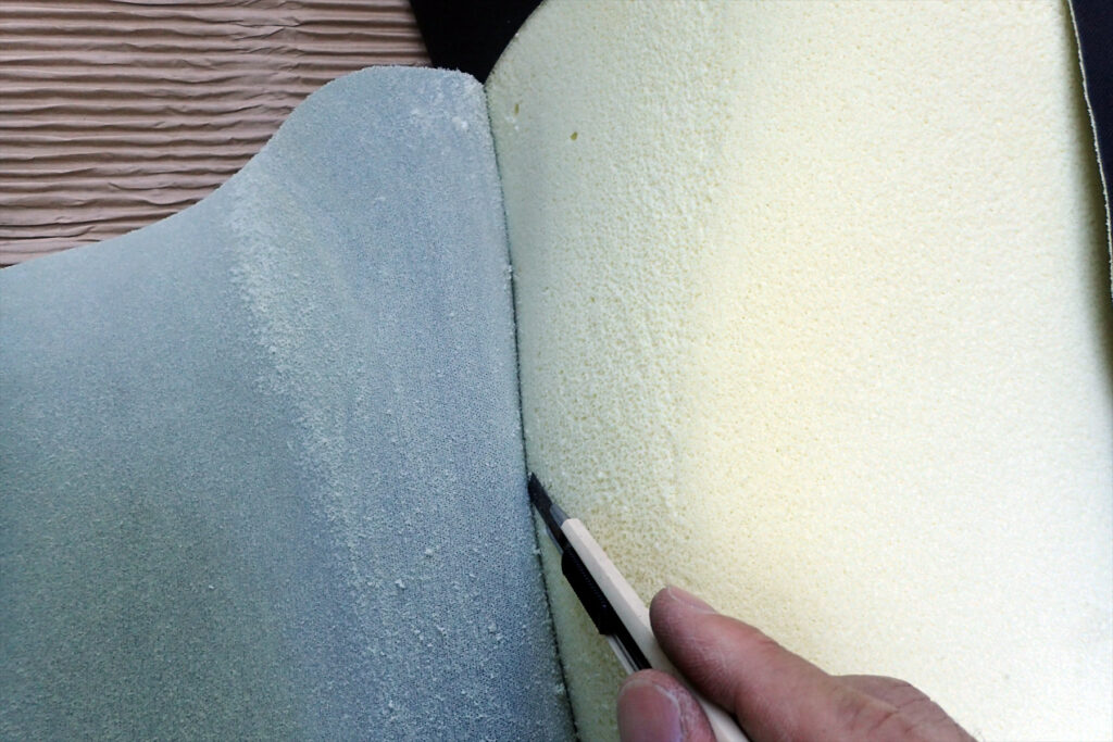 F650GSのハイシートの表皮を剥がしているところ.スポンジとシート表皮が接着されている