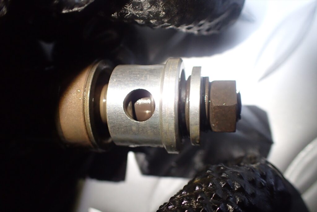 Macro close-up of the rebound valve assembly and oil ports on a ME08 front fork rod.