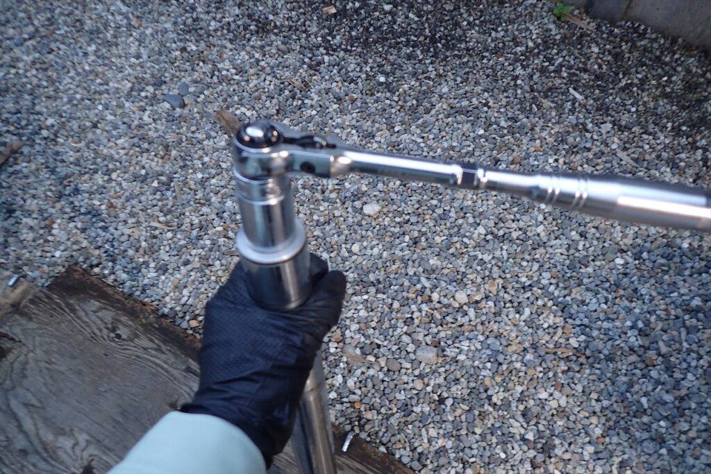 Loosening the front fork top cap of a Honda XR250 using a ratchet wrench and socket.