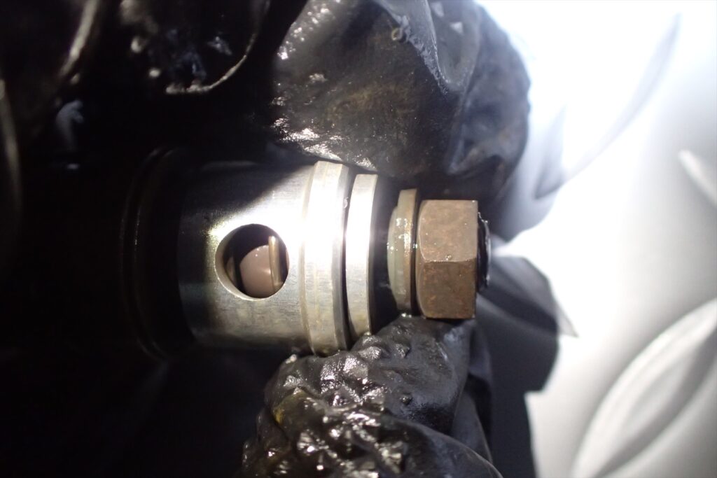 Detailed inspection of a motorcycle front fork piston valve component held by a gloved hand.