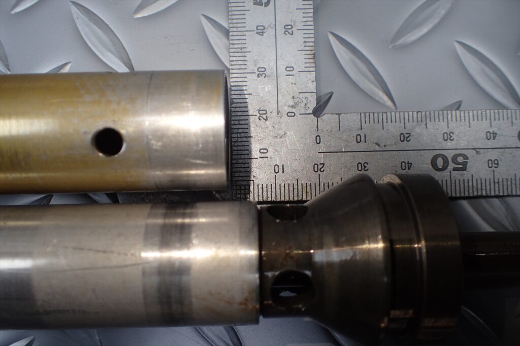 Measuring the exact length difference of front fork cylinders using a metal square ruler.