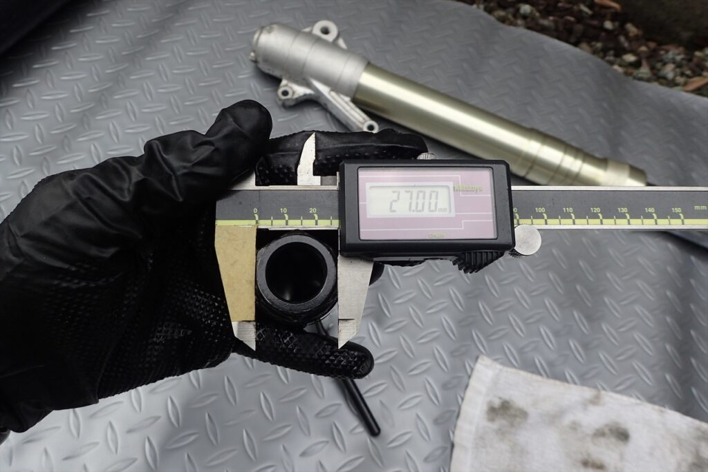 Measuring the 27.00mm diameter of a motorcycle suspension tool using a Mitutoyo digital caliper.