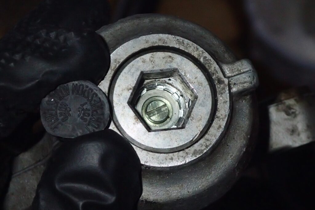 Close-up of the compression damping adjuster screw and rubber cap on the bottom of a Honda XR250R ME08 front fork.