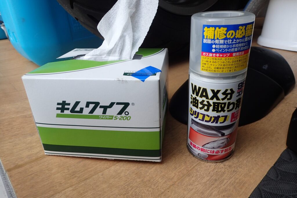 A box of Kimwipes S-200 paper and a can of Soft99 Silicone Off degreaser spray placed on a wooden floor.