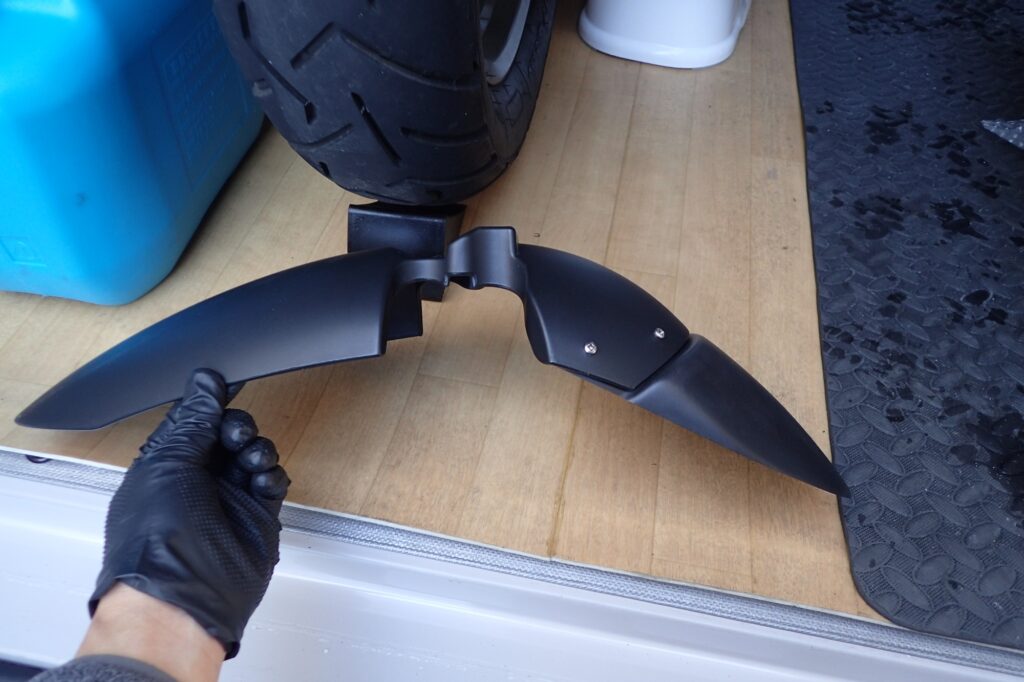 The full profile of a BMW G650GS front fender with the extender successfully secured using four metal screws, laid on the floor.