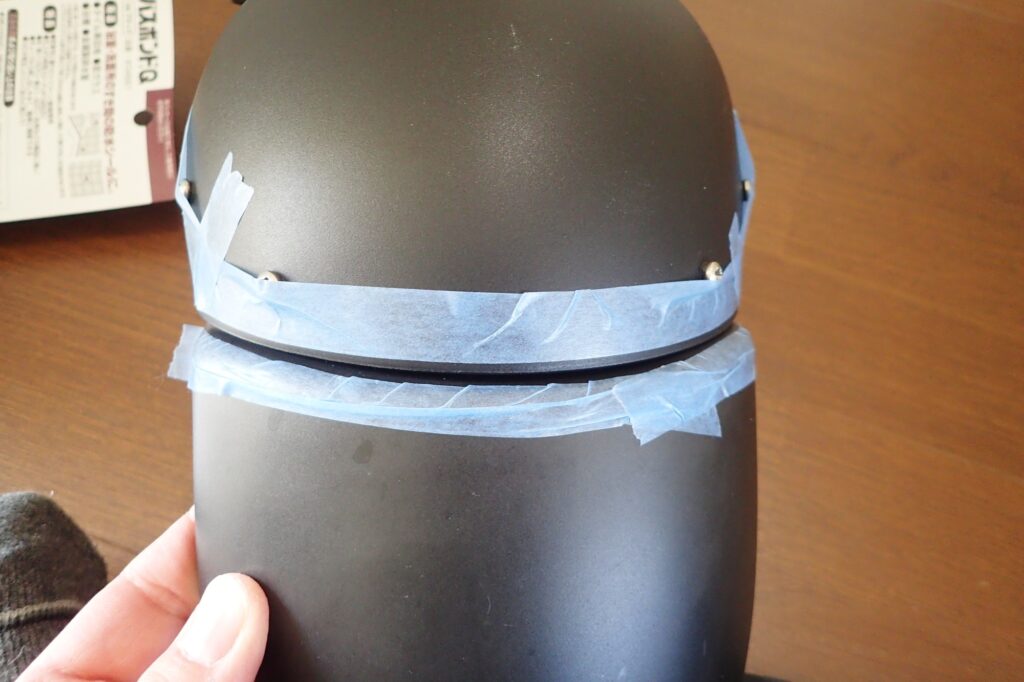 Blue masking tape applied precisely along the outer joint line of a motorcycle front fender for neat caulking preparation.