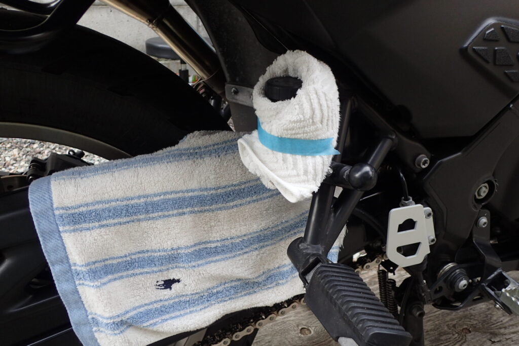 バイクのリアブレーキフルードタンクのフタを開けるために,周囲を養生する.