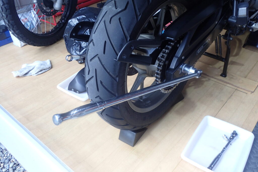 リアのアクスルシャフトをブレーカーバーを使って緩めているところ.