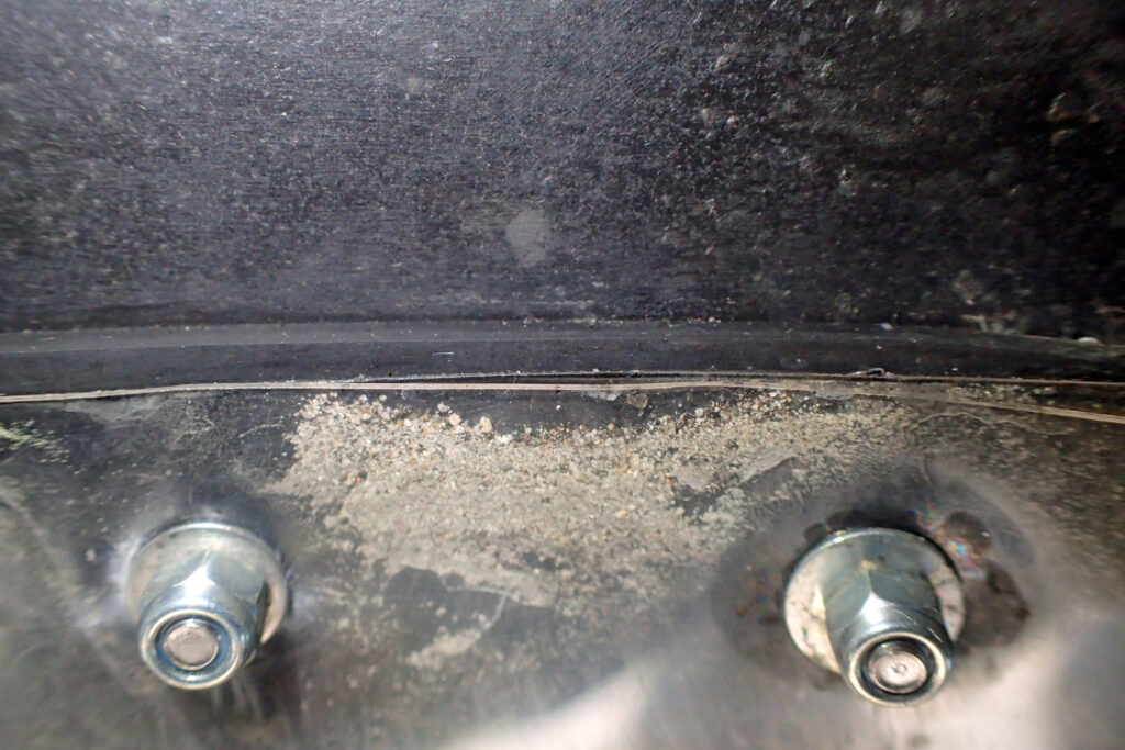 バイクのリアマッドガード延長部のボルト周辺をクローズアップ。継ぎ目やボルトの隙間に泥や砂が入り込んでいる状態のディテール画像。