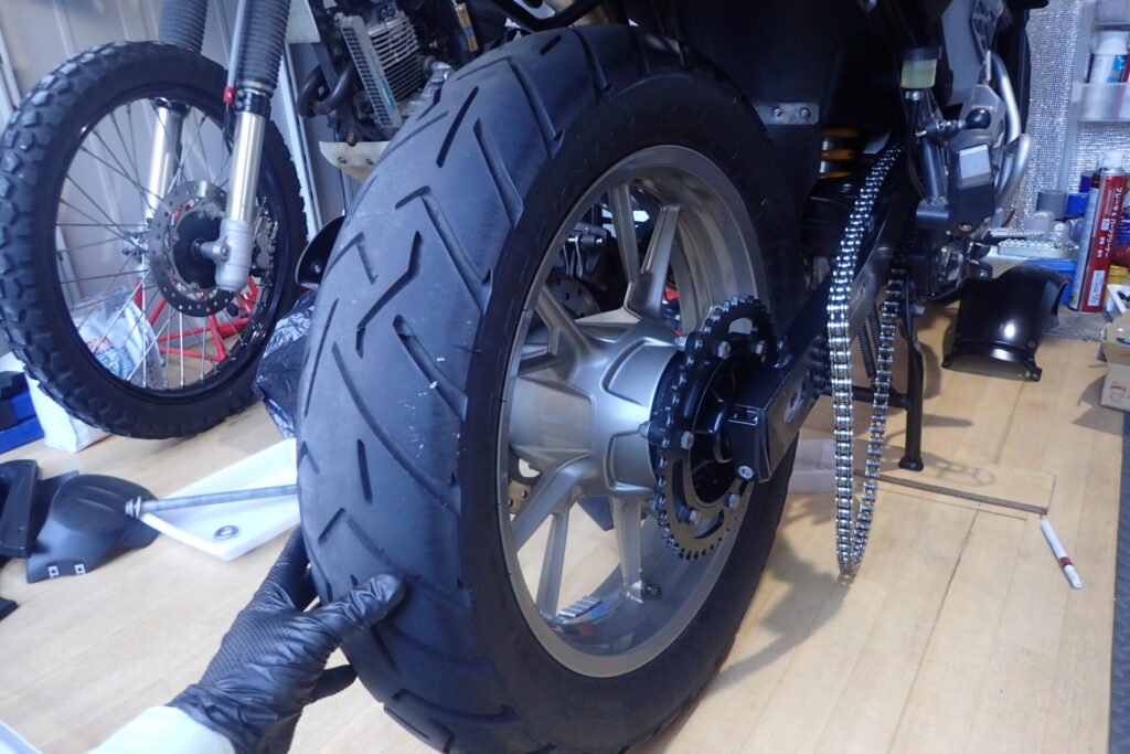 バイクのリアタイヤをスイングアームに取り付けているところ.