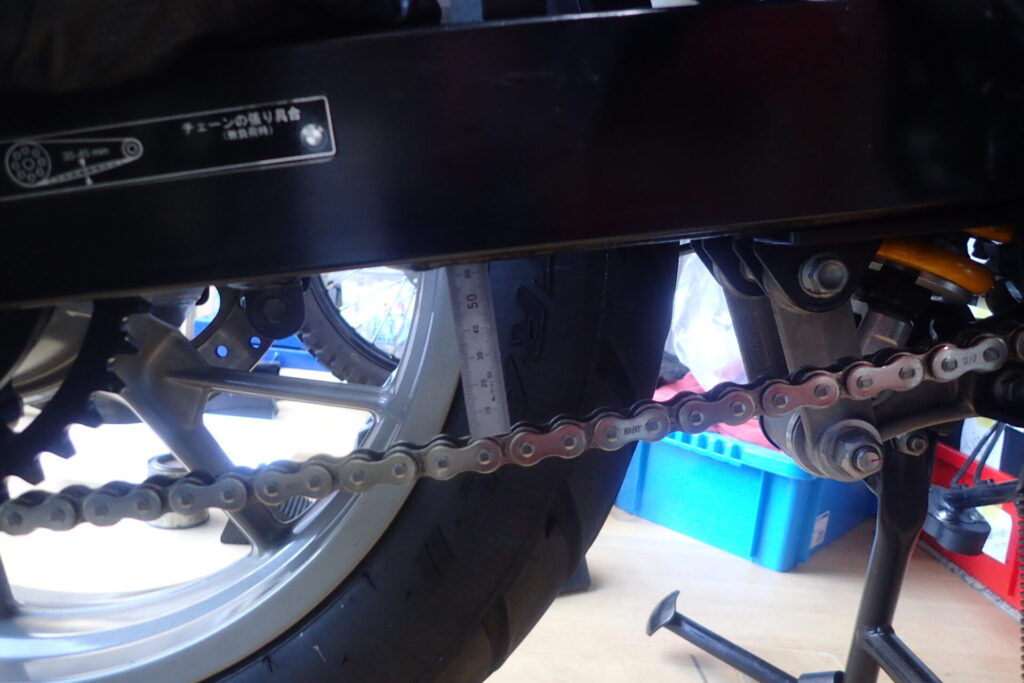 バイクのチェーンの張り調整のため,チェーンの張り具合を測っているところ.