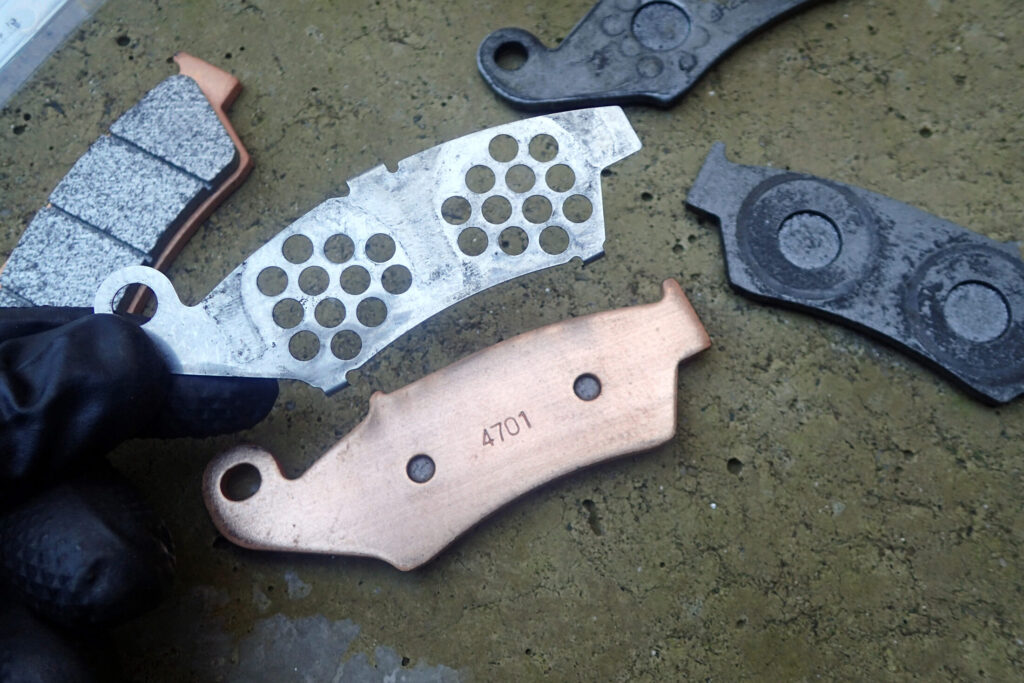 【新旧比較】 摩耗した古いブレーキパッド（溝なし）と新品のデイトナ ゴールデンパッドχの比較。斜めに当たっていた摩耗の様子。