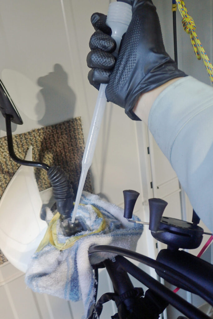 【フルード抜き取り】 新品パッド交換によるフルード溢れを防止するため、ブレーキフルードをスポイトで吸い取る作業。液面調整の重要性。