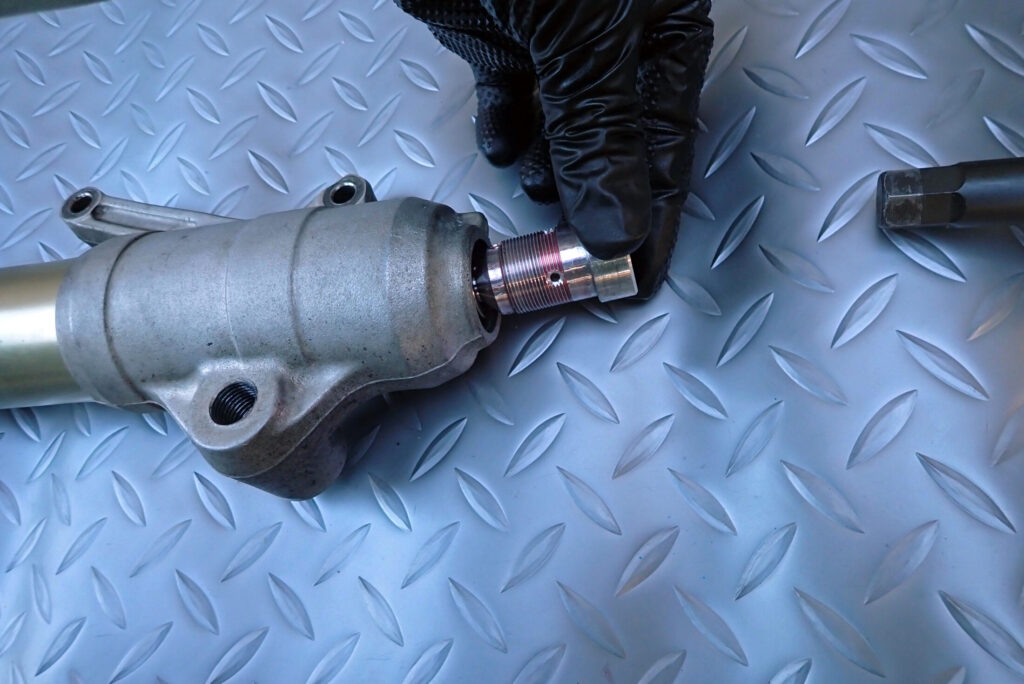 XR250 BAJAのフロントフォークを分解し，センタボルトを外している様子．