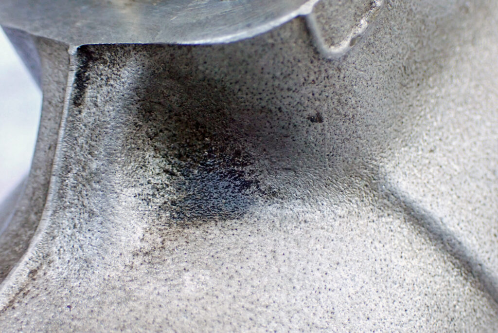 ブラシが届かない複雑な形状のバイクパーツに蓄積した頑固な泥汚れと酸化膜の接写