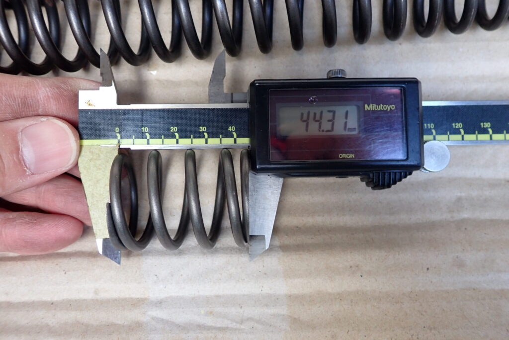 デジタルノギスを用いてXR BAJAのフロントフォークスプリングA（短い方）の自由長を計測する様子