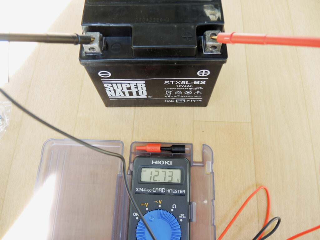 HIOKIのカードハイテスタ 3244-60でバイクのバッテリーの電圧を計測しているところ．