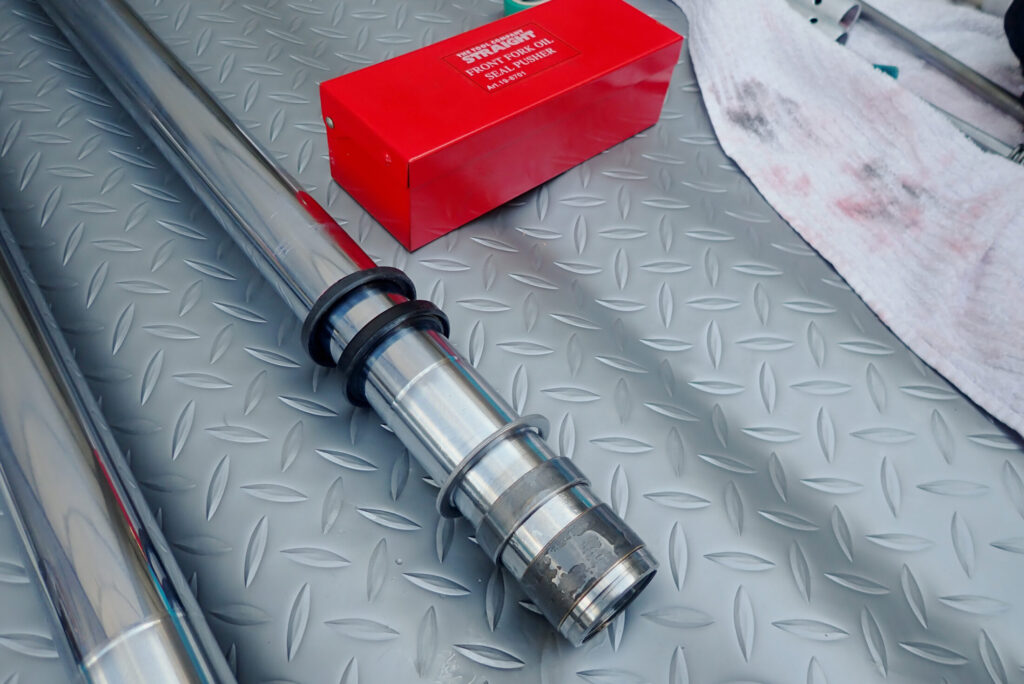 グリスアップしたフォークオイルシールとダストシールを、インナーチューブへ慎重に差し込む作業工程