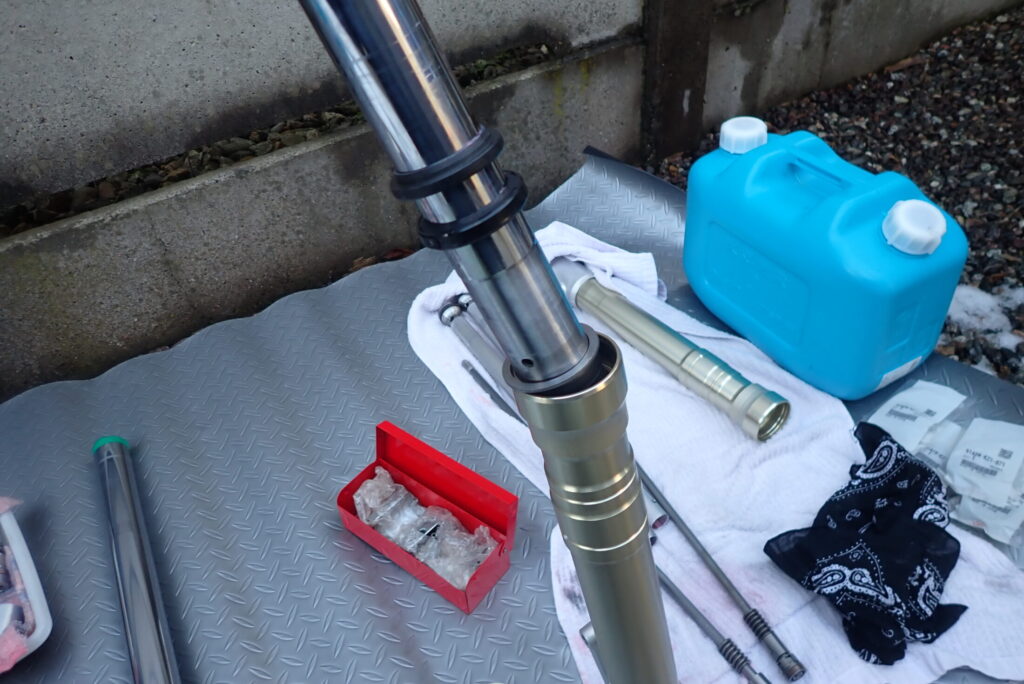 スライドメタル，フォークシール，ダストシール等を装着したインナーチューブを慎重にアウターチューブに挿入する様子．