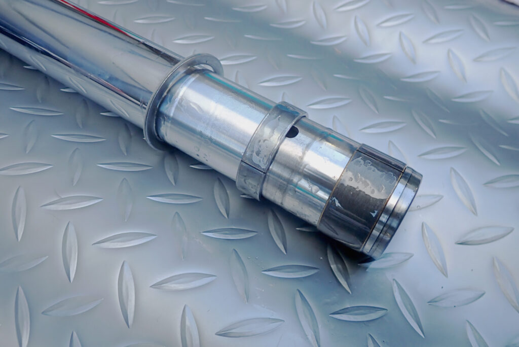 A.S.H.のフォークオイルを塗布したスライドメタル，スライドブッシュをインナーチューブに取り付けている様子．