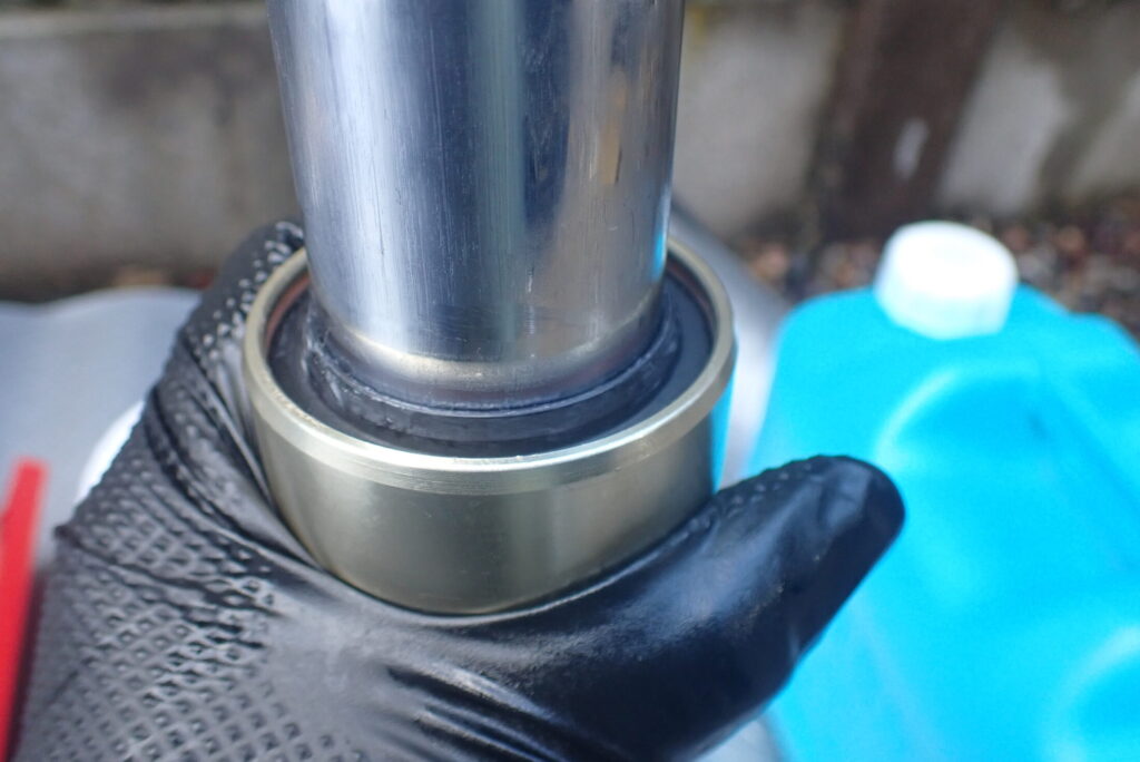 オイルシールの打ち込み完了後、ダストシールをアウターチューブ上端に指で押し込んで装着する様子