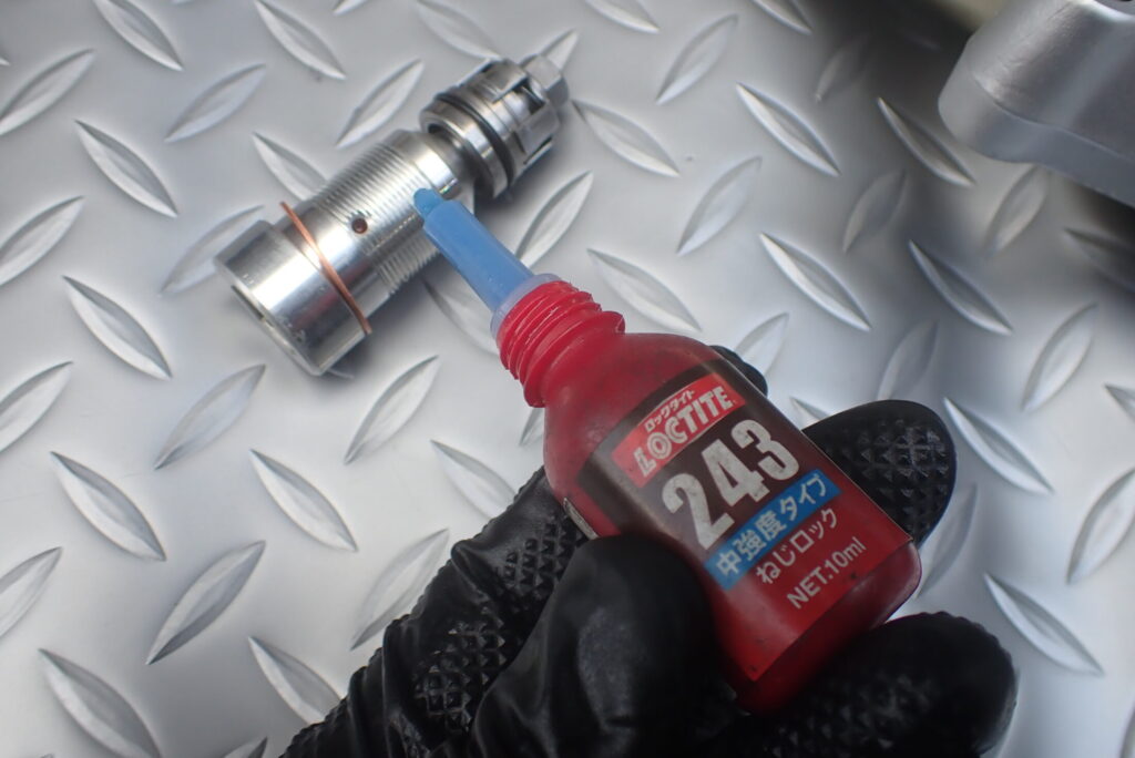 緩みとオイル漏れを防止するため、フロントフォーク底部のセンターボルトにネジロック剤を塗布する作業