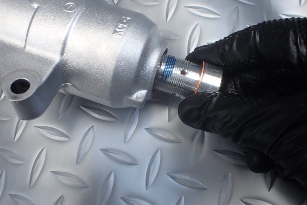 ネジロック剤を塗布したセンターボルトを慎重にボトムブラケットから挿入している様子．