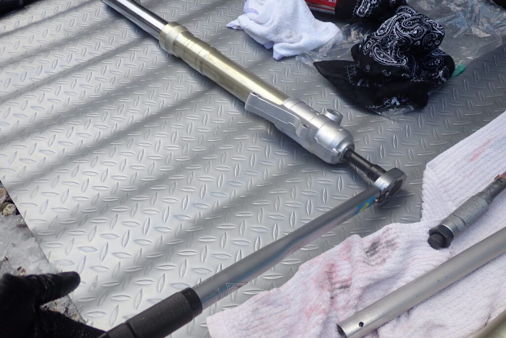 特殊工具でシリンダーの供回りを防ぎながら、14mmソケットでセンターボルトを規定トルクで締め付ける様子