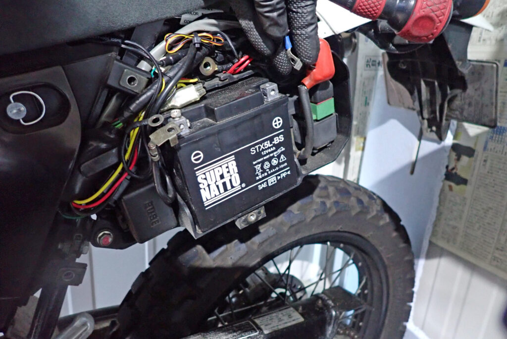 プラス(+)側の端子保護カバーをめくってボルトを外すバッテリー取り外し工程