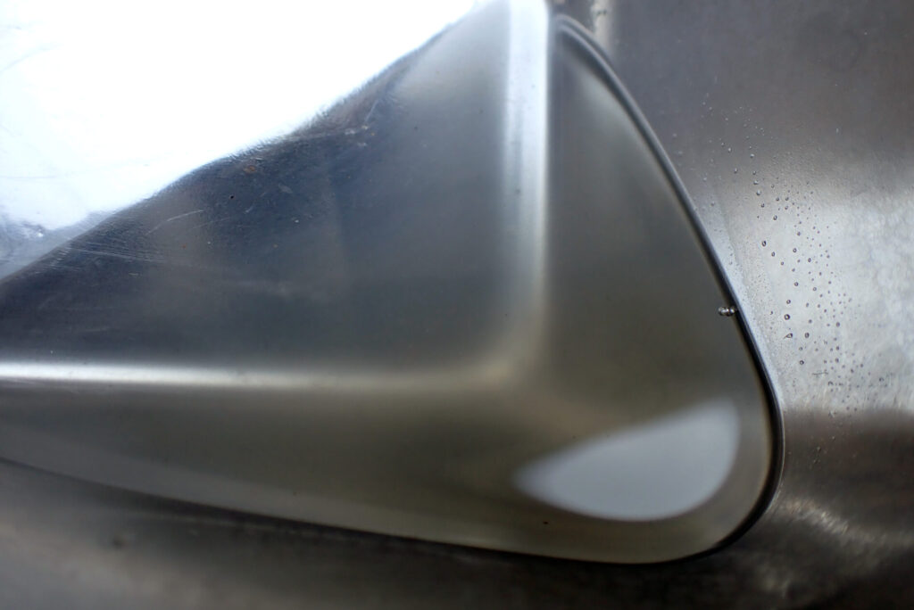 WPC処理後のスプリングをパーツクリーナーで洗浄した後の様子。洗油による汚れで少し濁った洗浄液。