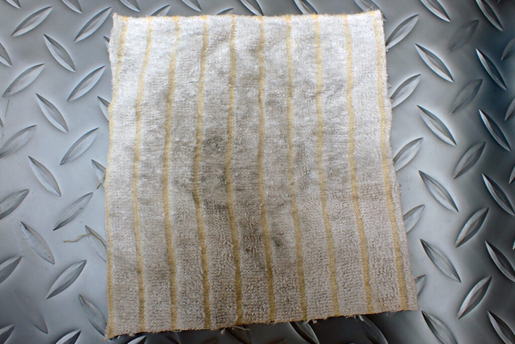 洗浄後のフォークスプリングを拭き取った際に付着した汚れが確認できるウエス。装着前の清浄作業の重要性を示す。