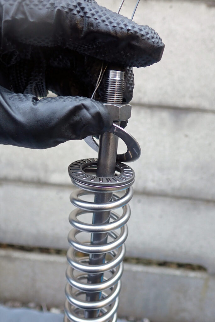 XR250 BAJAのフロントフォークにスプリングの初期動作が滑らかになるようにスラストベアリングを入れる様子．