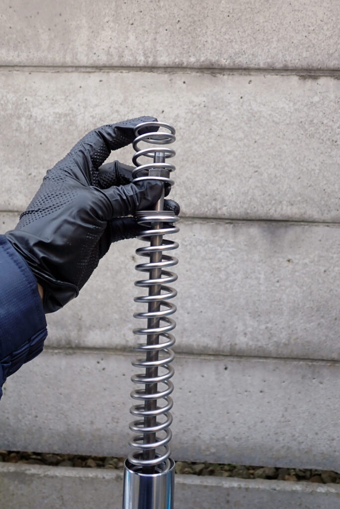 XR250 BAJAのフロントフォークにスプリングの初期動作が滑らかになるようにスラストベアリングを入れる様子．