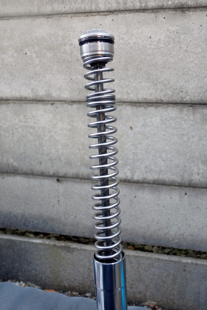 XR250 BAJAのフロントフォークスプリングとスラストベアリングの装着が完了し，トップボルトを取り付けた様子．