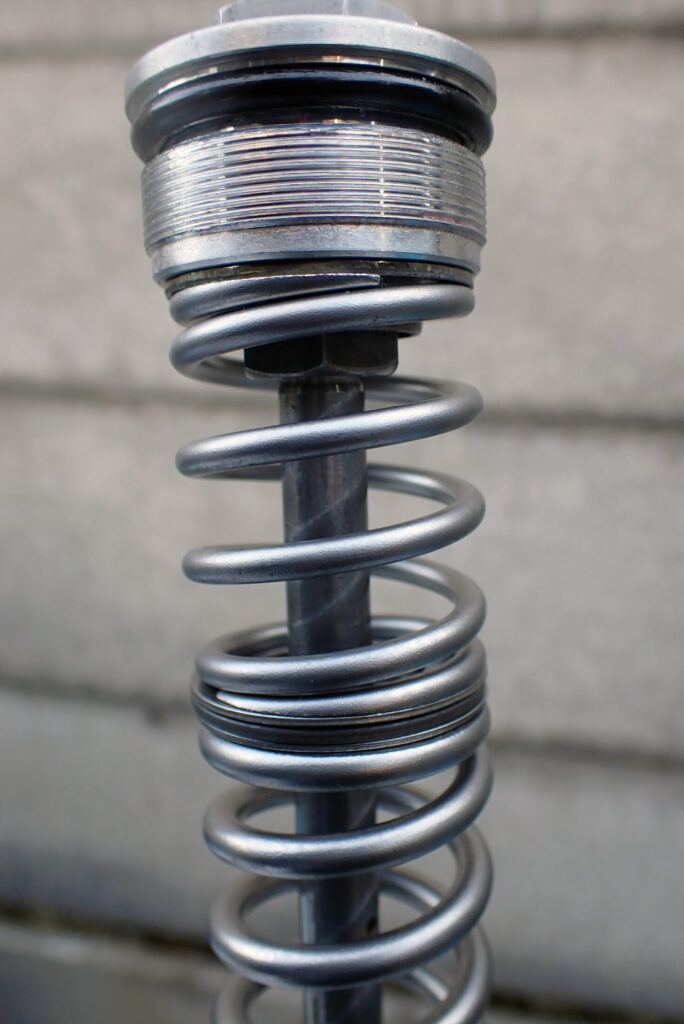 XR250 BAJAのフロントフォークに取り付けたスラストベアリングの外径が，スプリングの外径と一致し，スラストベアリングの装着に問題がないことを確認する様子．