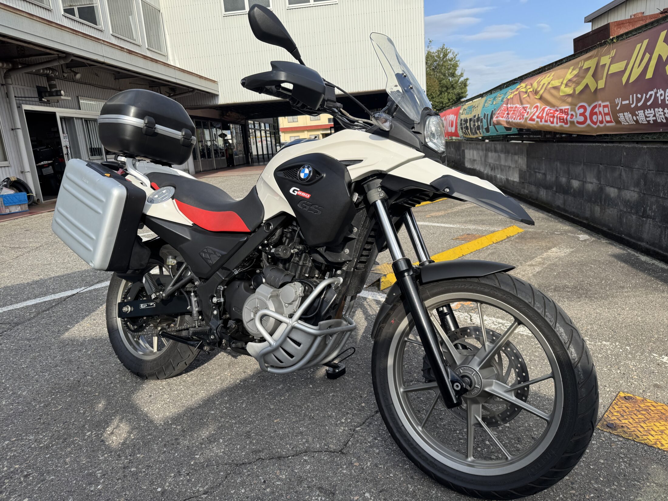 A white BMW G650GS fitted with panniers and a top box