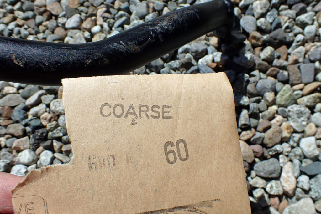 エンジンガードの古い塗装とサビを耐水ペーパーで削り落とす足付け作業の様子