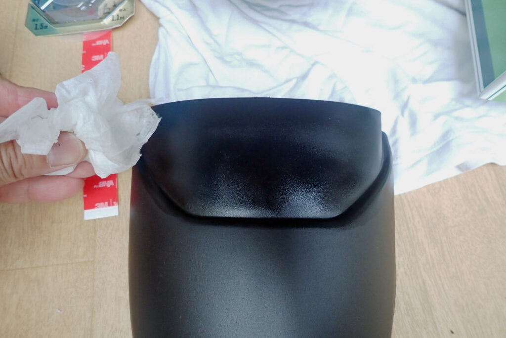 Degreasing the bonding surface of the front fender extender flap using a degreasing spray and a Kimwipe.