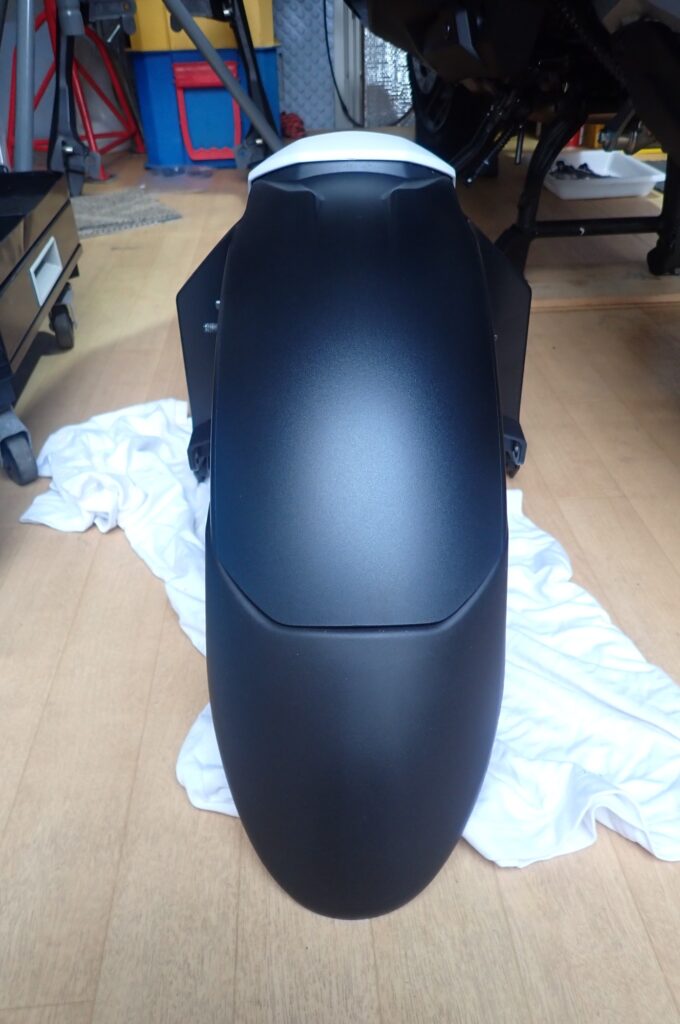 The matte black front fender extender successfully attached and assembled onto the original Honda X-ADV 750 front fender.