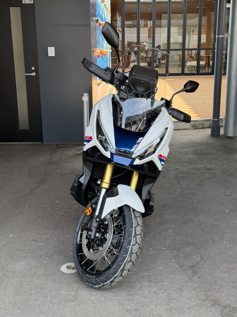 Close-up front view of the Honda X-ADV 750 Special Edition, highlighting the aggressive dual LED headlights, windscreen, and premium gold inverted front forks.