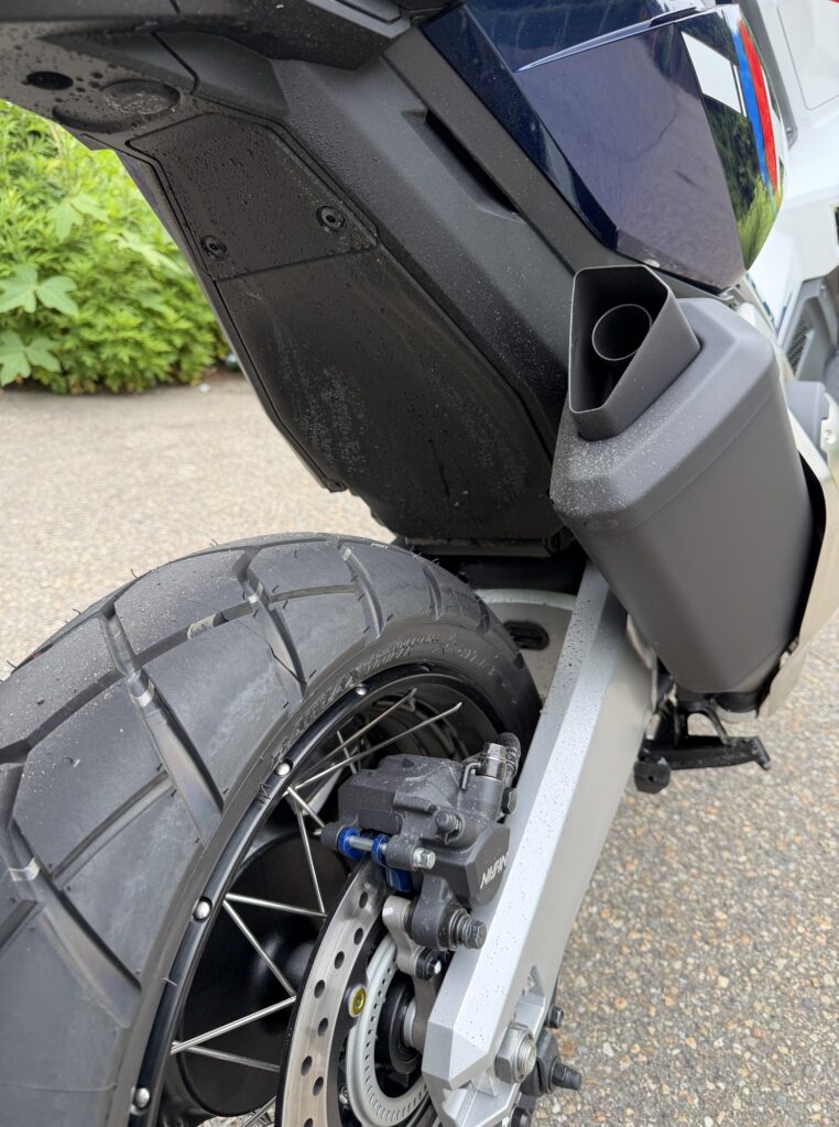 Close-up of the rear left side of a Honda X-ADV, demonstrating that the left indicator remains clean compared to the right side.