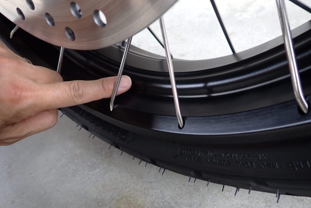 A finger pointing at the wide gap between spokes on the Honda X-ADV front wheel, showing easy access for maintenance.