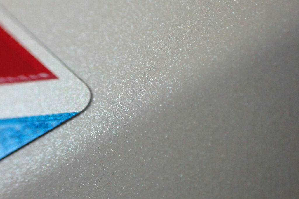 Macro photography of the glossy white pearl paint on a Honda X-ADV motorcycle, showcasing glittering pearl flakes after applying liquid glass coating.