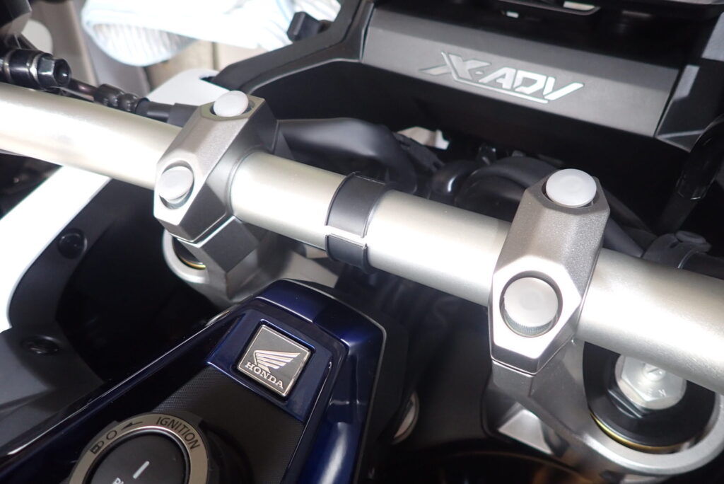 A black rubber spacer placed on the center of the silver tapered handlebar of a Honda X-ADV motorcycle.