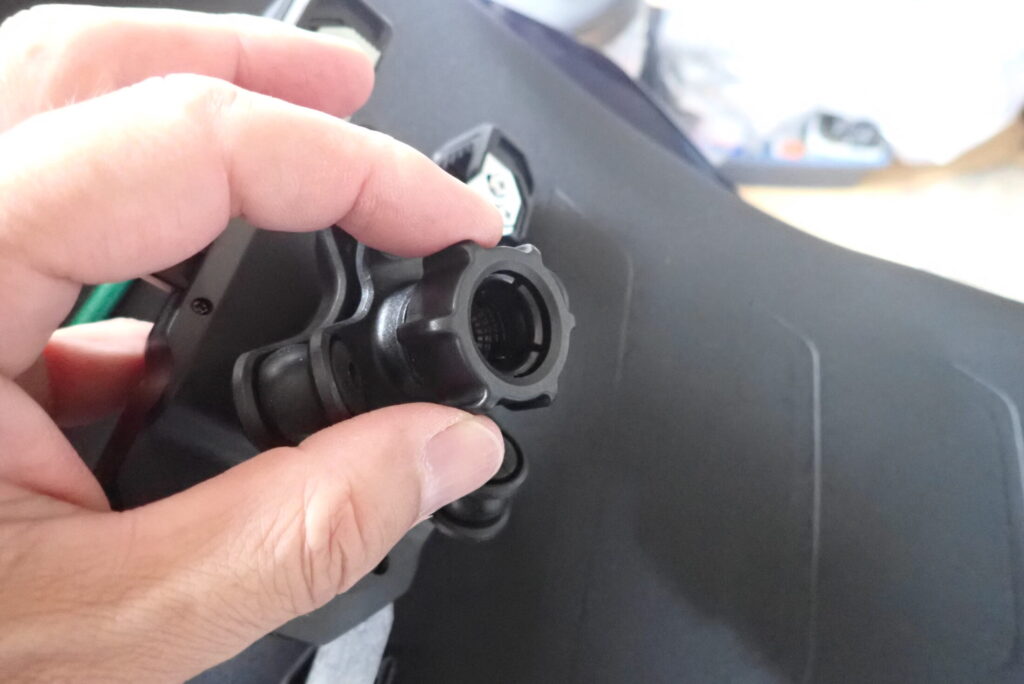 A hand adjusting the plastic tightening nut on the back of the Kaedear motorcycle phone holder body.