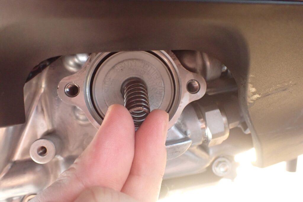A hand checking the correct outside direction text stamp on a new yellow paper Honda DCT oil filter cartridge, matching it with the internal return spring.