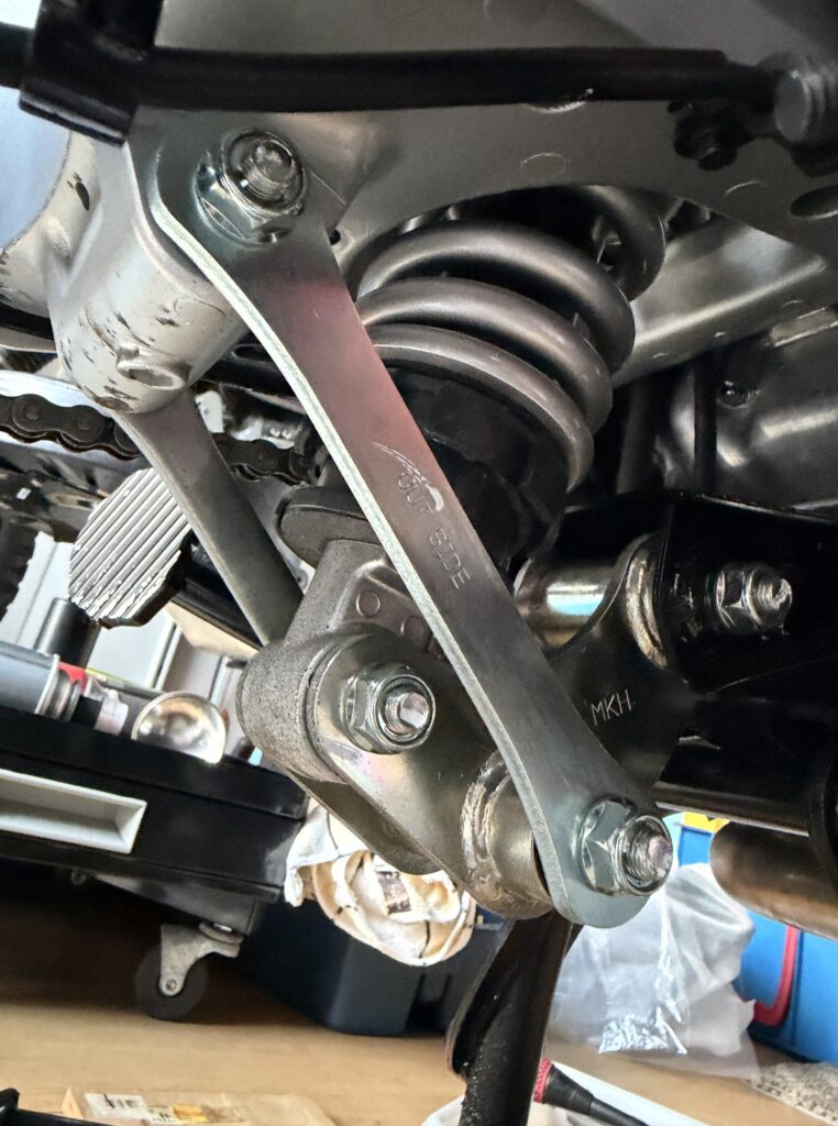 Underbody view focusing on the rear suspension linkage pivot bolts and collars ready for DIY greasing maintenance.