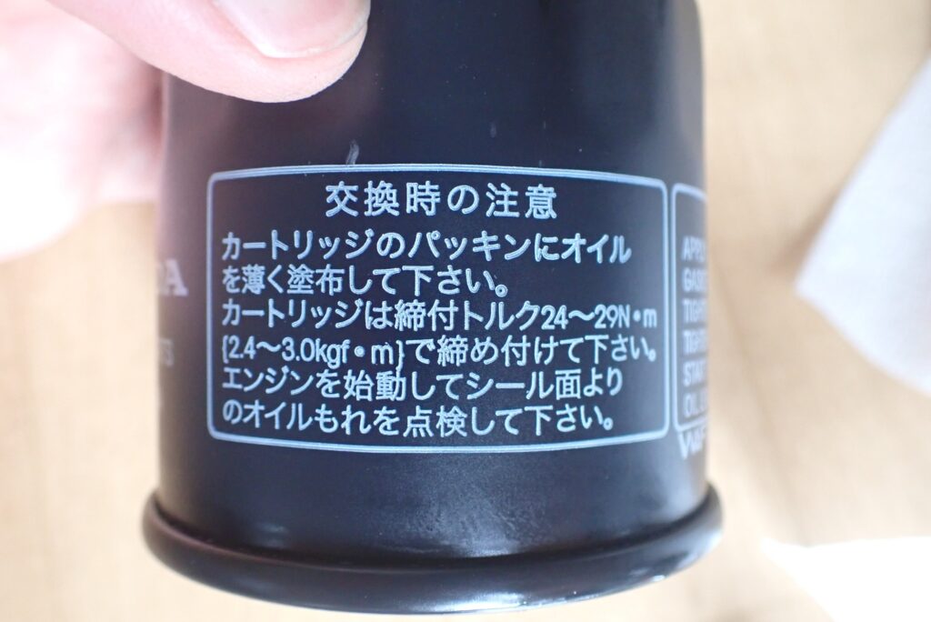 A new genuine Honda motorcycle oil filter cartridge showing the printed installation torque specifications of 24 to 29 Newton-meters on its label.