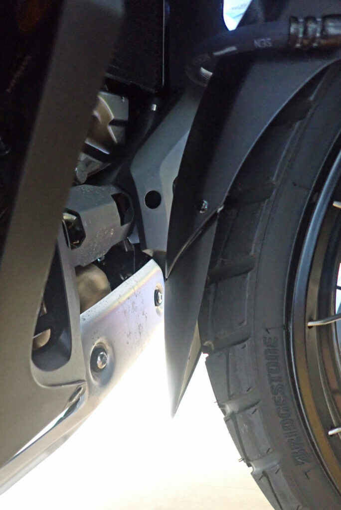 Close-up view of the installed matte black front fender extender on a Honda X-ADV 750, showing the clearance between the tire, fender, and lower engine cowl.