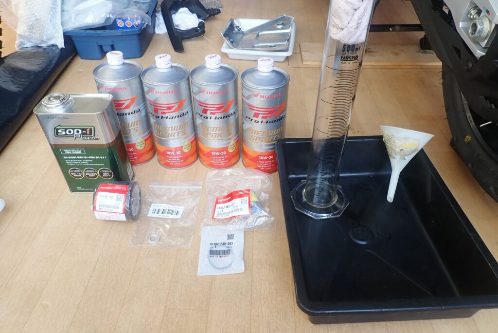 A complete motorcycle oil change kit containing Honda Ultra G3 oil cans, SOD-1 Plus fluid, OEM engine filter, DCT filter, O-ring, funnel, and a glass measuring cylinder.